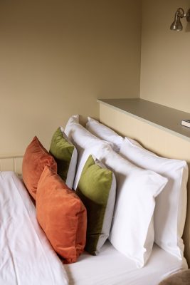 the top end of the bed with 8 pillows inside a shepherds hut at Great Ashley Farm.