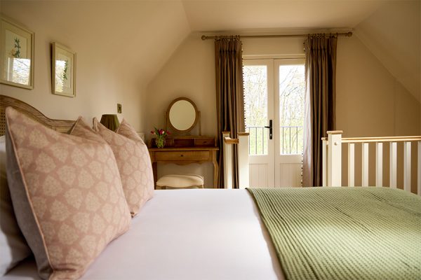 a view across the bed and outwards the balcony at Wisteria, a holiday cottage at Great Ashley Farm in Bradford-On-Avon